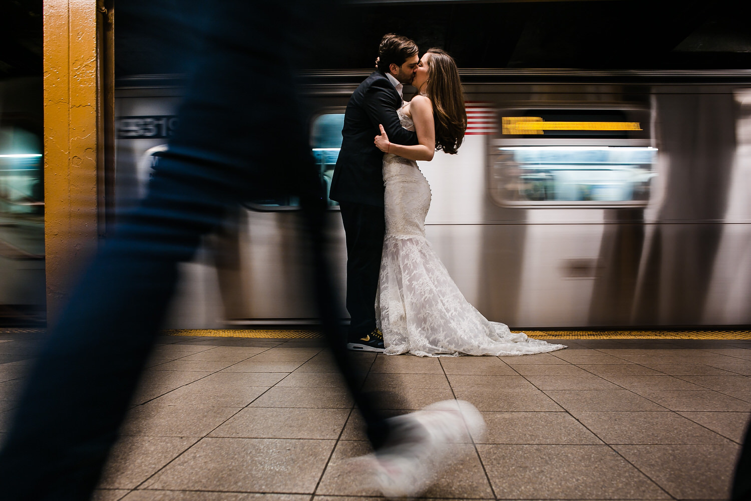 Novios besándose en un andén de metro mientras pasa un tren