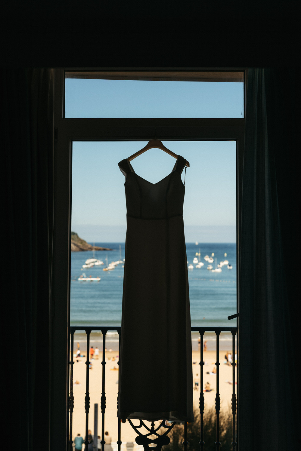 Vestido de novia colgado frente a una ventana con vistas a la playa